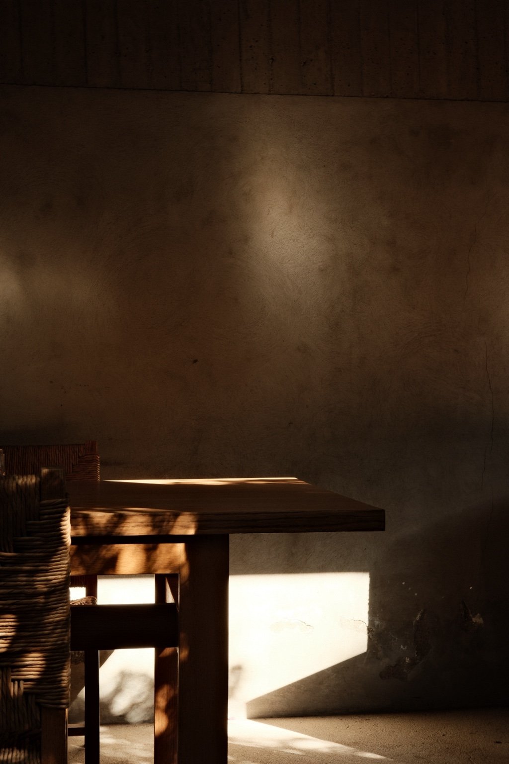 Operational consultancy for private homes: a wooden table and rush chair in late sunlight against a plaster wall