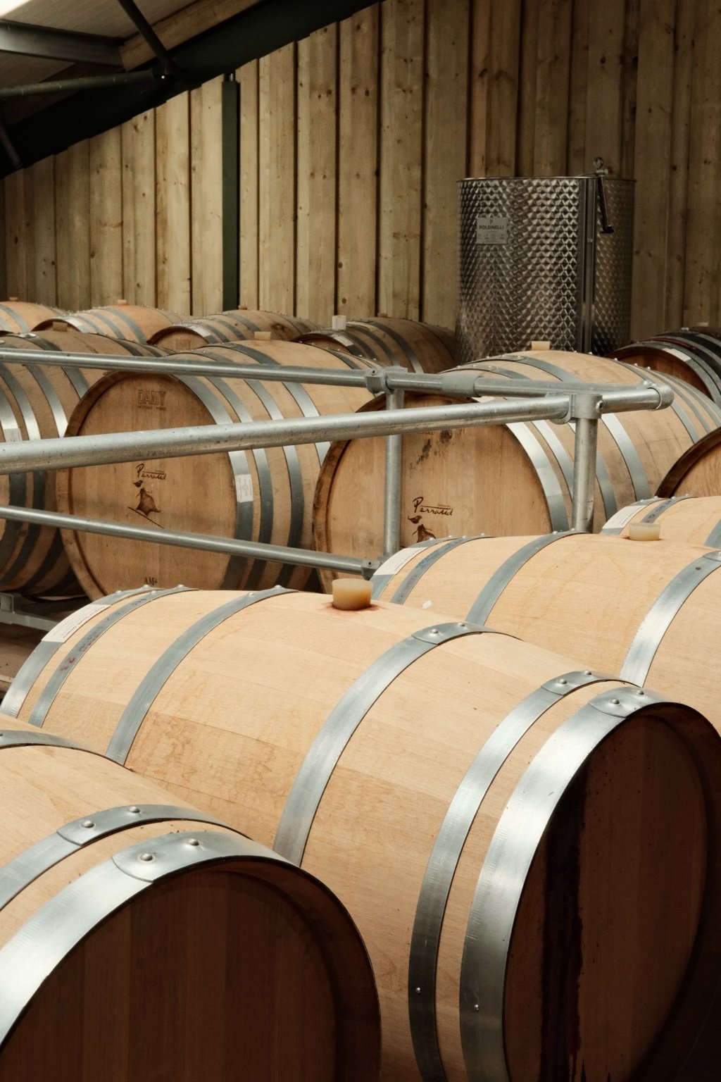 Curated wine experiences: oak wine barrels resting in rows in a timber clad winery
