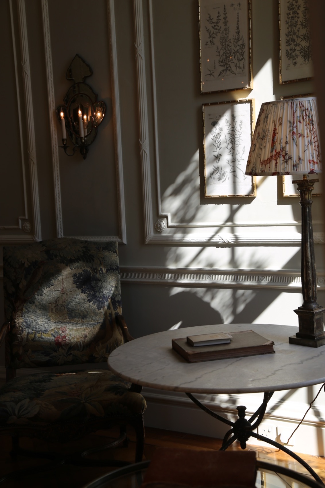 Property and interiors: a panelled drawing room with a tapestry chair and marble table in afternoon light