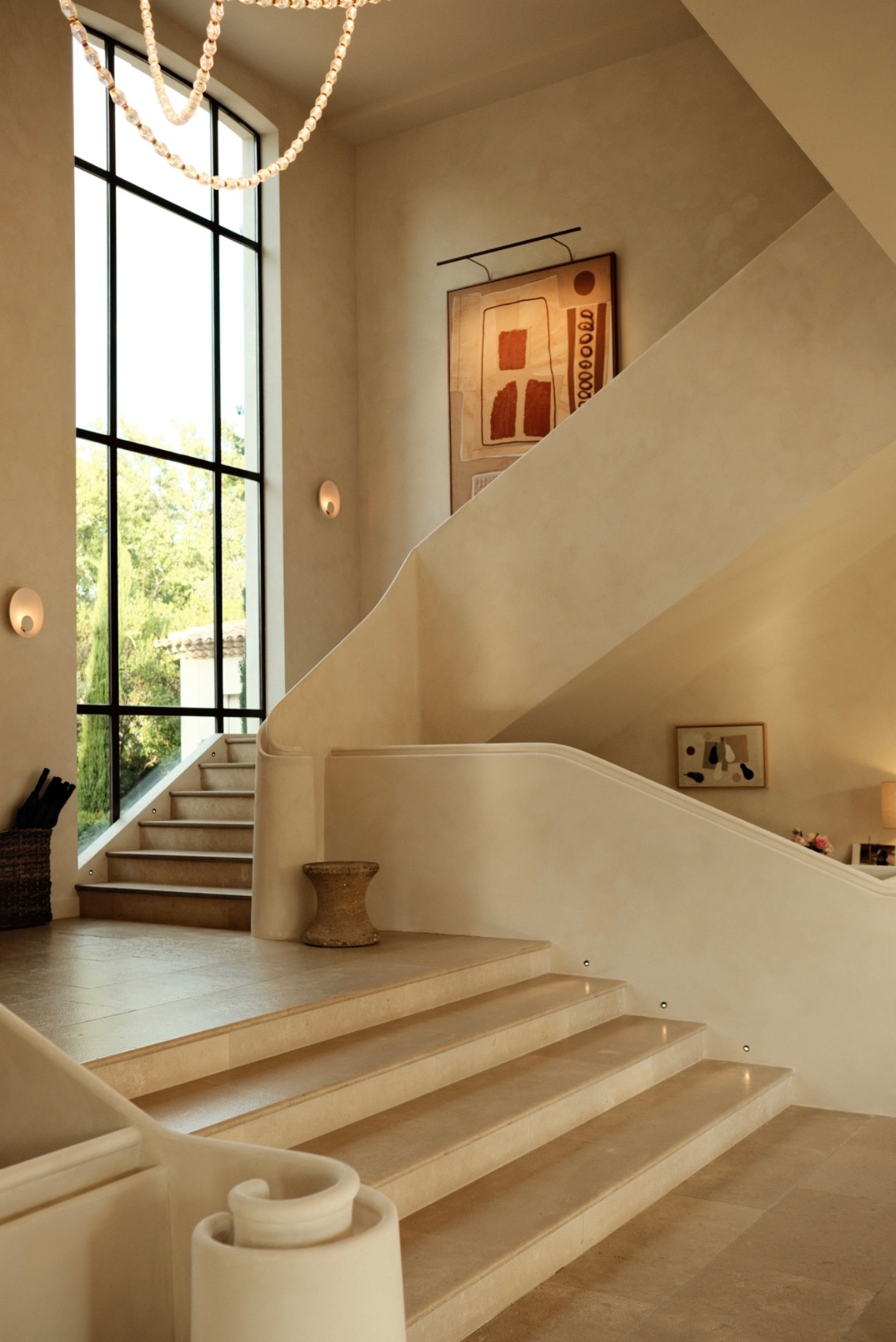 A pale limestone staircase rising beside a tall steel window